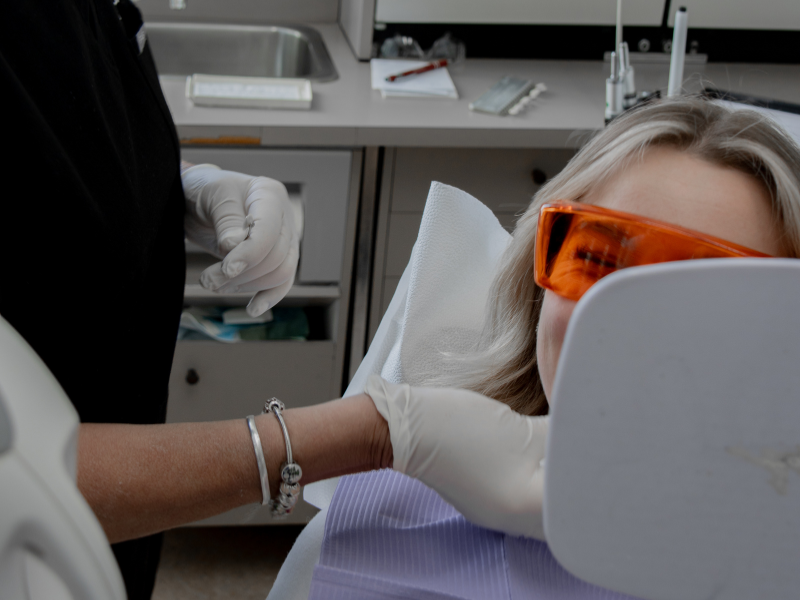Une patiente se regarde dans le miroir après un traitement de dentisterie esthétique, plus précisément un blanchiment des dents, à la clinique dentaire Ecodentaire à Montréal.