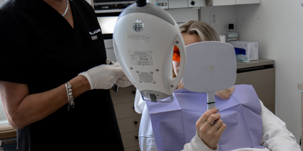 Une patiente se regarde dans le miroir après un traitement de dentisterie esthétique, plus précisément un blanchiment des dents, à la clinique dentaire Ecodentaire à Montréal.