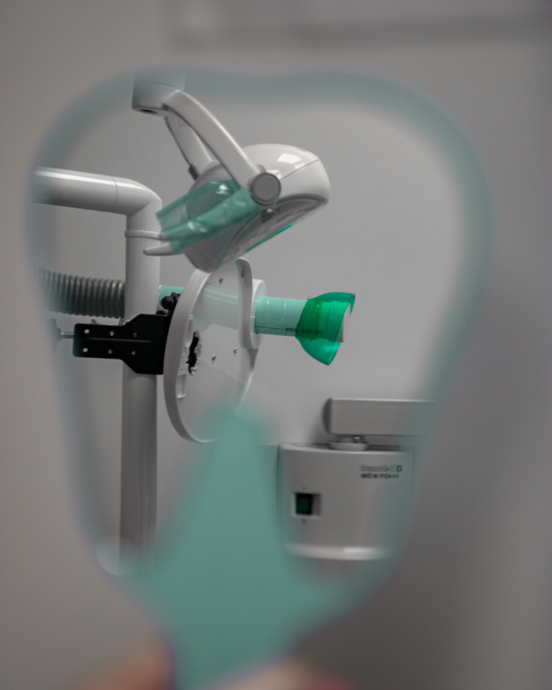 Image d’une salle de soins dentaires reflétée dans un miroir, où les dentistes de la Clinique Ecodentaire prodiguent leurs traitements dentaires. | Soins dentaires | Dentiste écologique | Clinique dentaire